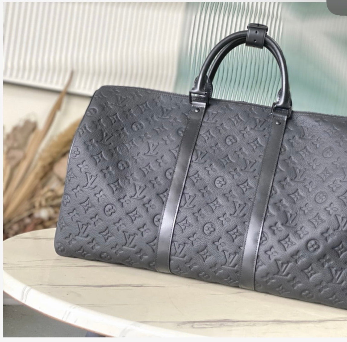 Gray embossed handbag with brand logo on a white surface